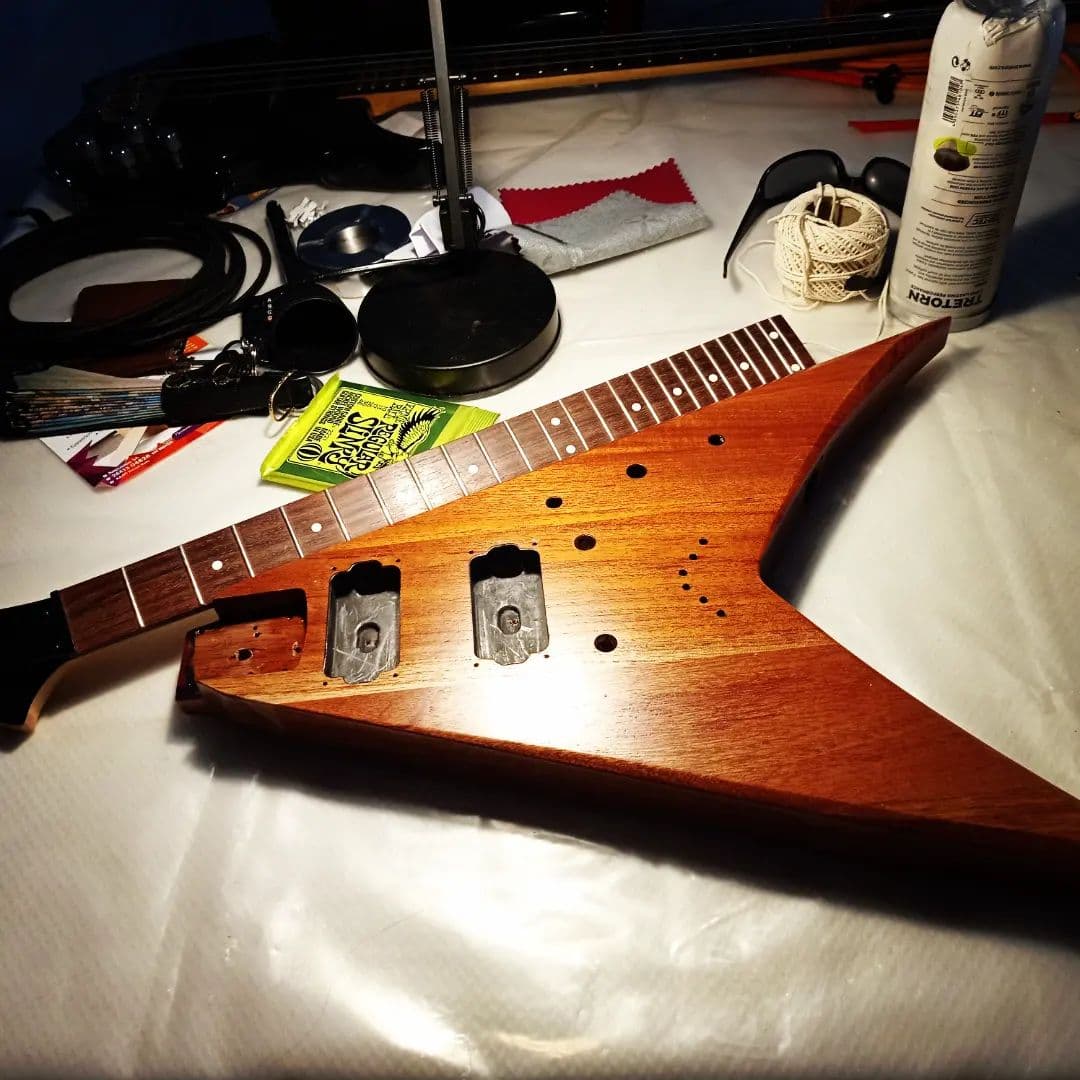 Flying V guitar body on the workshop bench, surrounded by tools and strings.