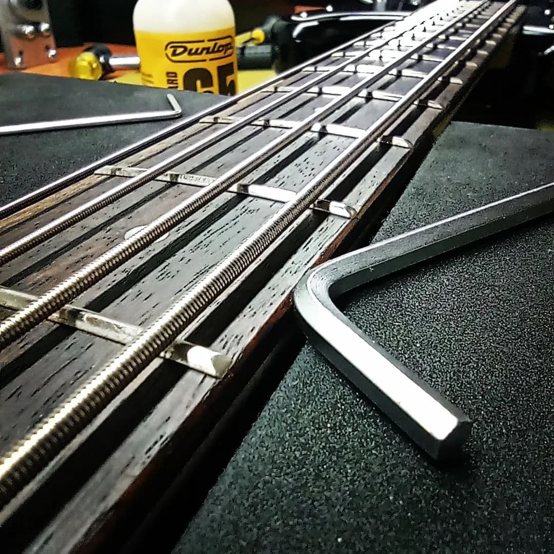 Bass fretboard during a fret-level and setup, with an Allen key alongside the frets.